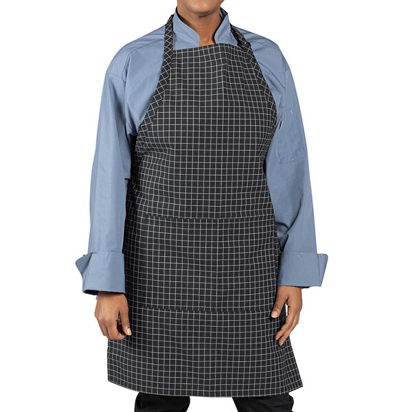 A person wearing a black and white checkered Uncommon Chef butcher apron with pockets.
