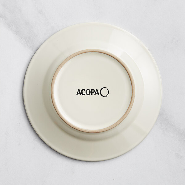 An ivory stoneware plate with a circular embossed rim and black text that says "Acopa" on it.