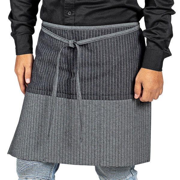 A man wearing a black and grey pinstripe Uncommon Chef waist apron.