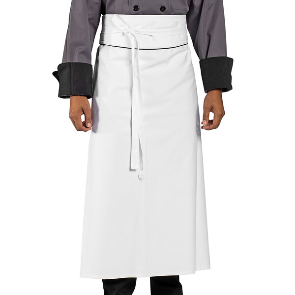 A person wearing a white Uncommon Chef executive apron with black piping.
