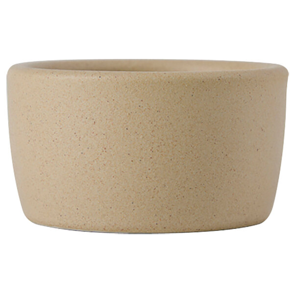A close up of a Tuxton matte beige ceramic ramekin.