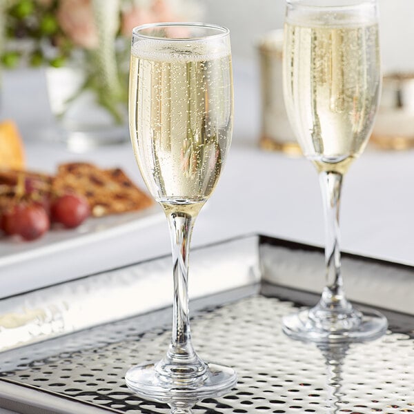 Two Acopa flute glasses of champagne on a tray.
