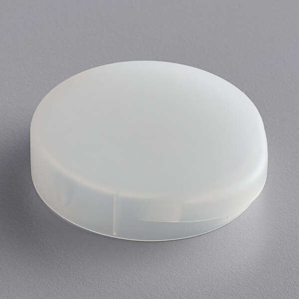 An American Metalcraft white plastic cap on a gray surface.