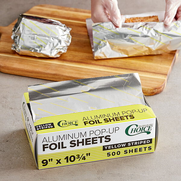 A person cutting Choice yellow striped foil sheets with a knife.