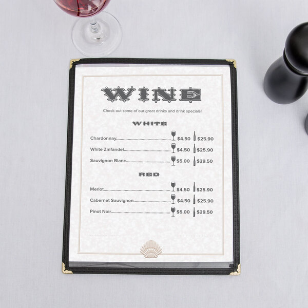 An 8 1/2" x 11" tan menu with a shell border on a table with a glass of wine.