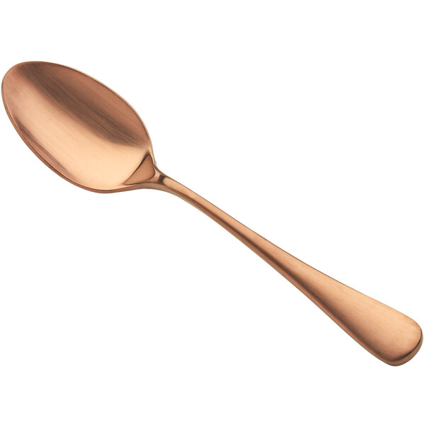 A close-up of a Bon Chef matte rose gold soup/dessert spoon with a handle.