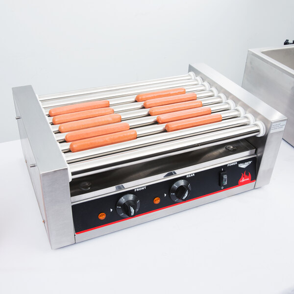 A Vollrath hot dog roller grill with hot dogs on it.