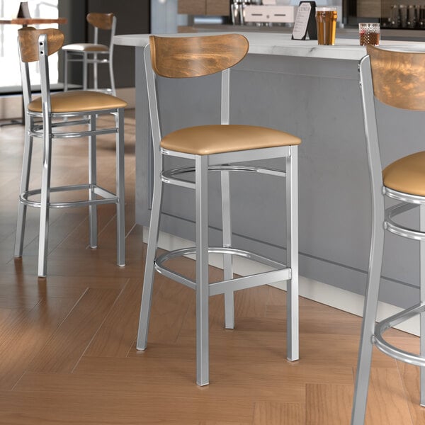 A group of Lancaster Table & Seating Boomerang Series bar stools with light brown vinyl seats and vintage wood backs.