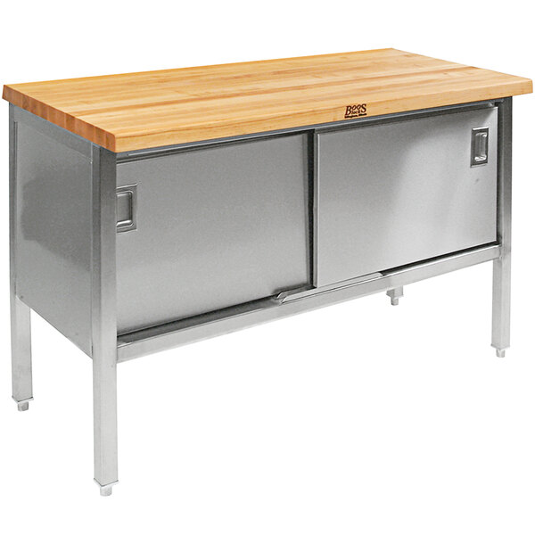A John Boos wood top work table with a stainless steel base and sliding doors.