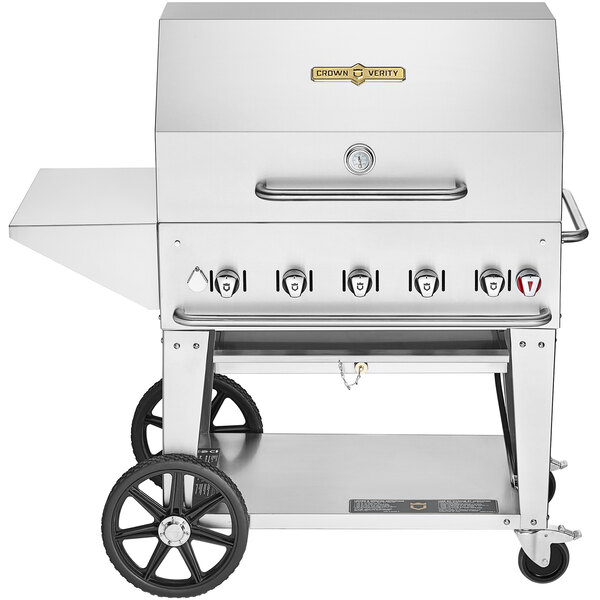 A silver Crown Verity portable outdoor barbecue grill with stainless steel top and wheels.