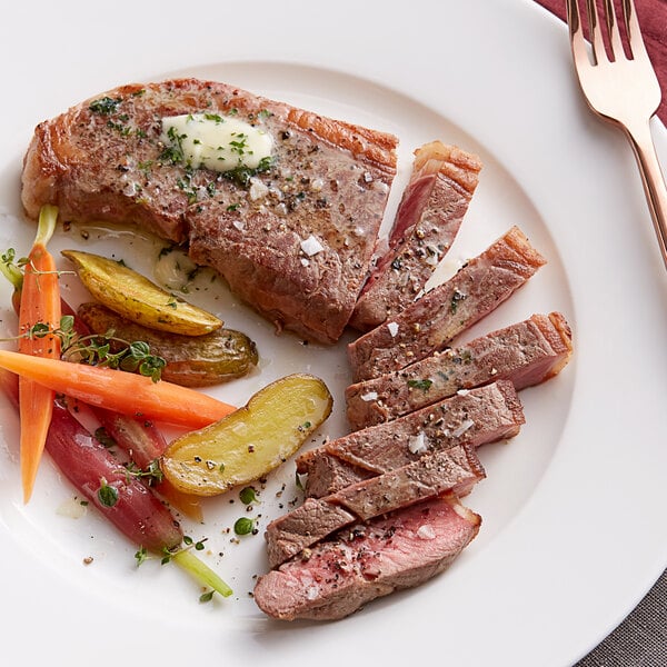 A plate of Kinikin Processing Rocky Mountain New York Strip Steak with carrots and potatoes.