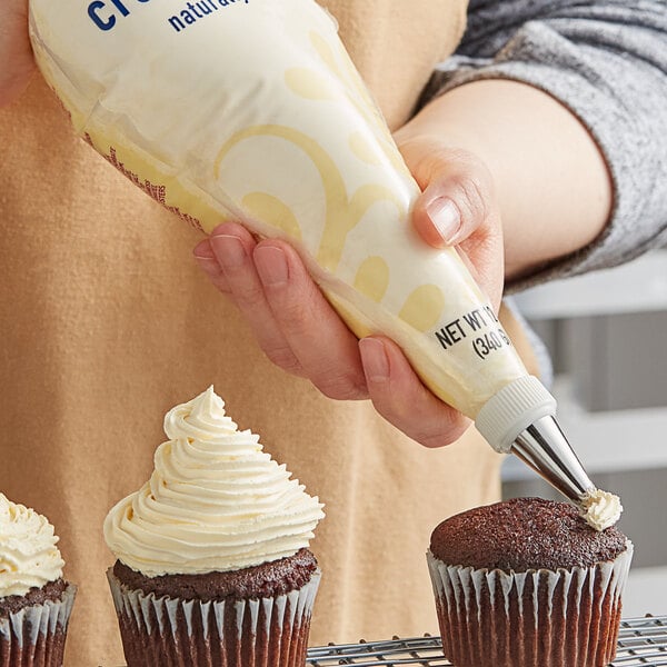 A person using a Rich's Bettercreme Cream Cheese Whipped Icing bag to frost a cupcake.