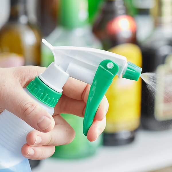 A hand holding a Noble Chemical green plastic spray bottle sprayer.