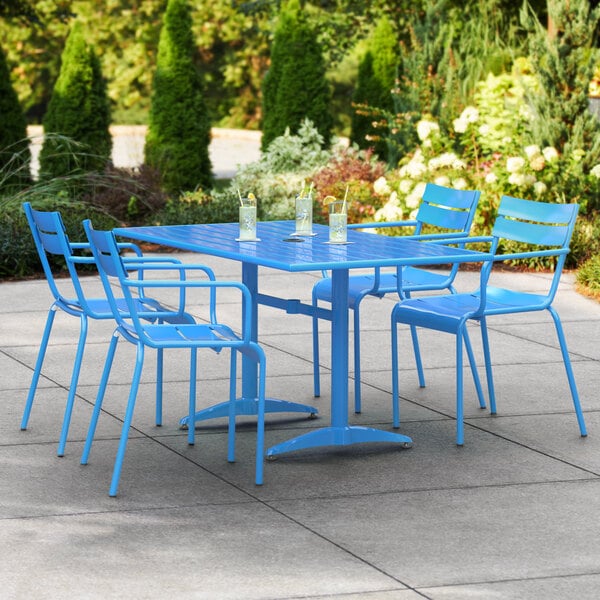 A blue table with 4 chairs on a patio.