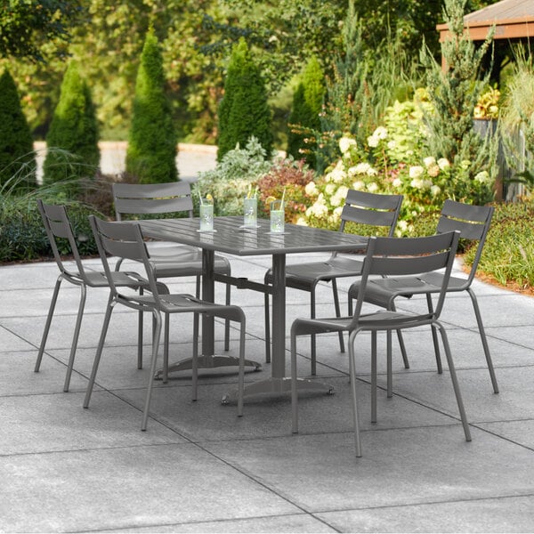 A Lancaster Table & Seating outdoor dining table with chairs on a tile patio.