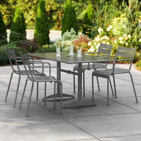 A Lancaster Table & Seating outdoor dining table with chairs on a patio.