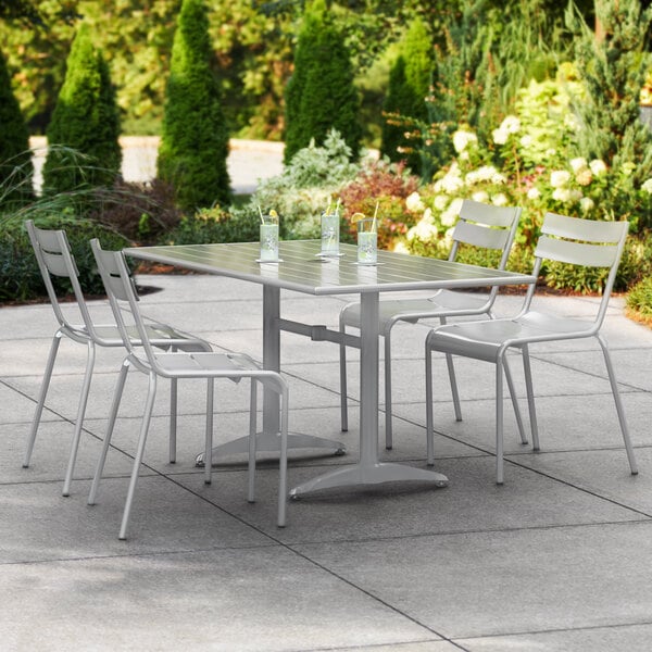A Lancaster Table & Seating outdoor table with chairs on a patio with a white umbrella.