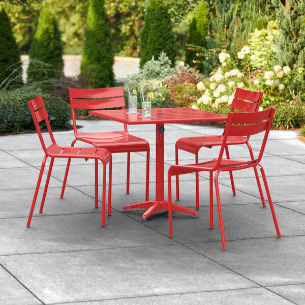 A red Lancaster Table & Seating outdoor dining table with chairs on a patio.