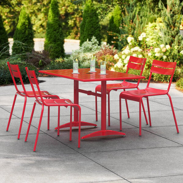 A red Lancaster Table & Seating outdoor dining table with chairs on a patio.