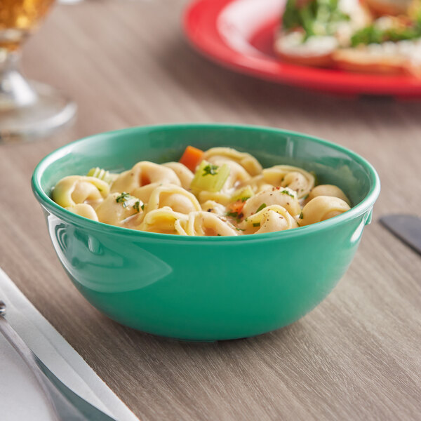 A green Acopa Foundations melamine nappie bowl filled with food on a table.