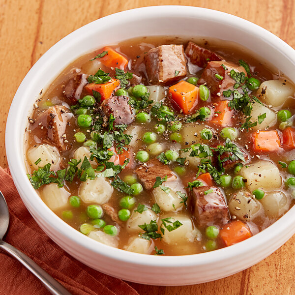 A bowl of College Inn beef broth soup with vegetables and meat.
