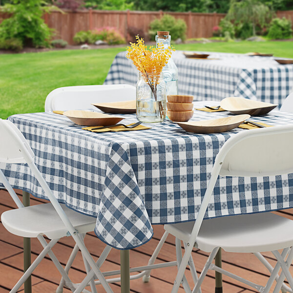 A table set with white plates on a table with a navy checkered tablecloth.