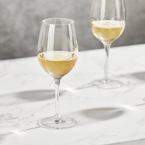 Three Della Luce Maia white wine glasses on a marble table.
