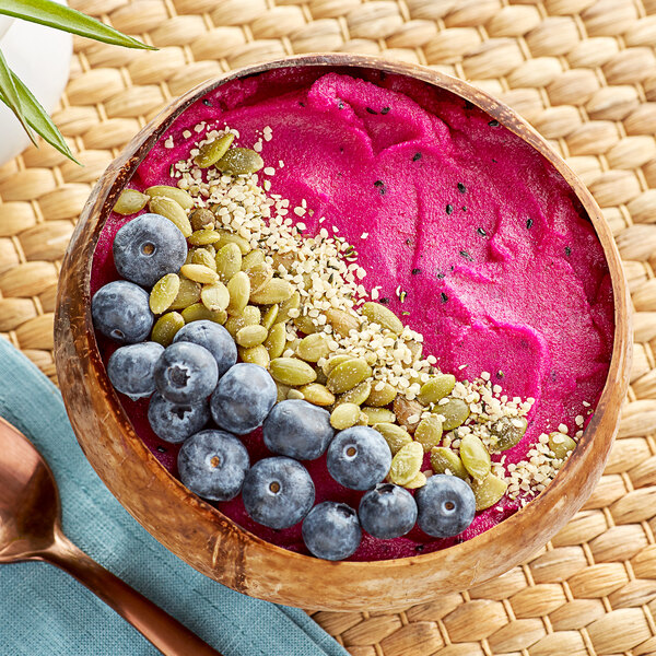 A bowl of pink Pitaya sorbet topped with blueberries and nuts.