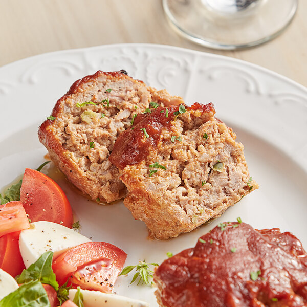 A plate of meatloaf with salad and tomato sauce.