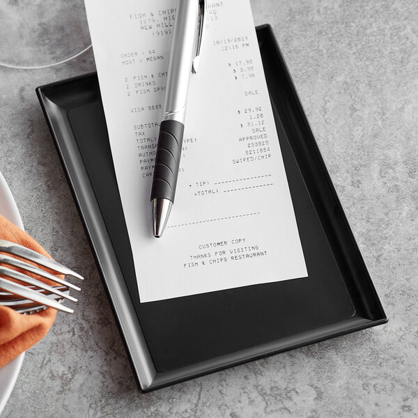 A pen and a receipt on a Vollrath black tip tray.