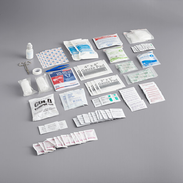 A Medique first aid kit refill with various first aid supplies on a gray surface.