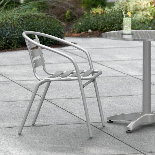 A Lancaster Table & Seating silver outdoor arm chair on a patio.