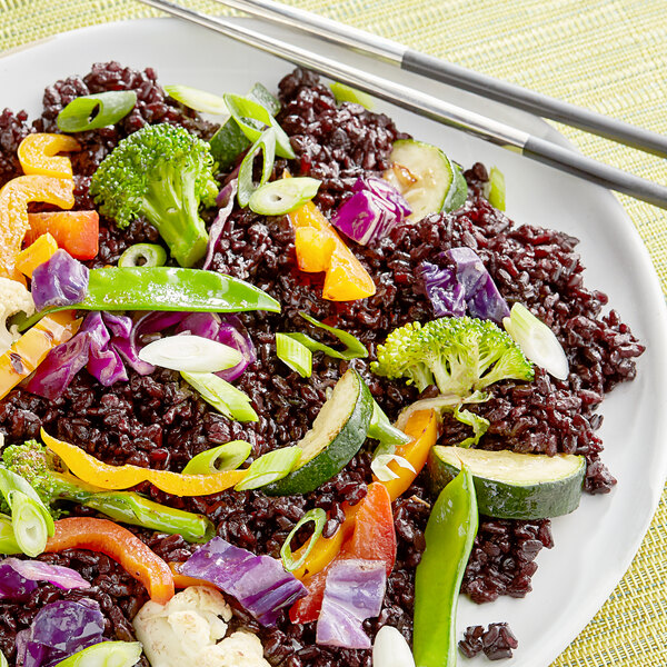 A plate of Campanini Venere black rice with vegetables and chopsticks.