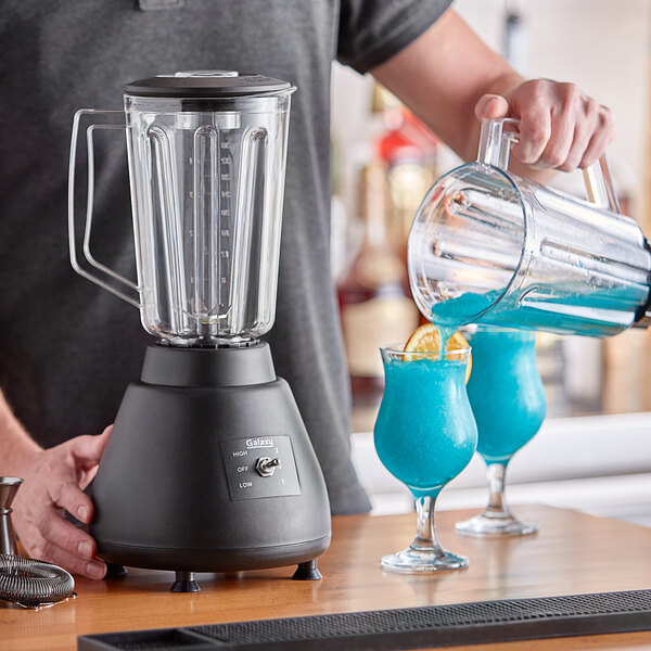 A man pouring blue liquid into a Galaxy commercial bar blender.