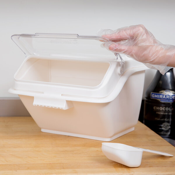 A hand in a plastic glove holding a Baker's Mark clear plastic container.