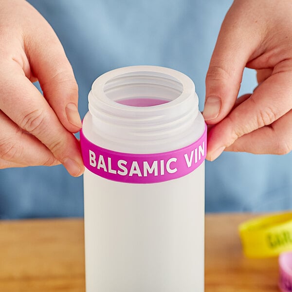 A person holding a plastic bottle with a white label band that says "Balsamic Vin"