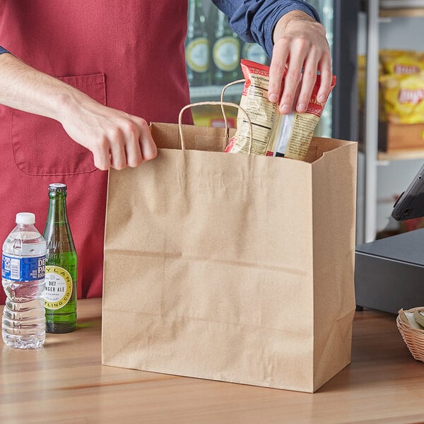 A person putting food in a brown paper shopping bag.
