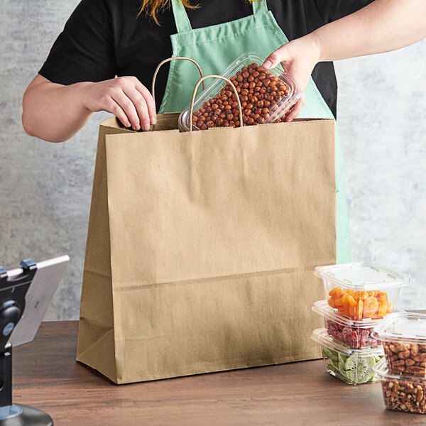 A woman holding a Choice Natural Kraft paper bag full of food.
