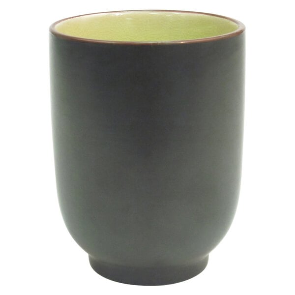 A black stoneware cup with a golden green rim.