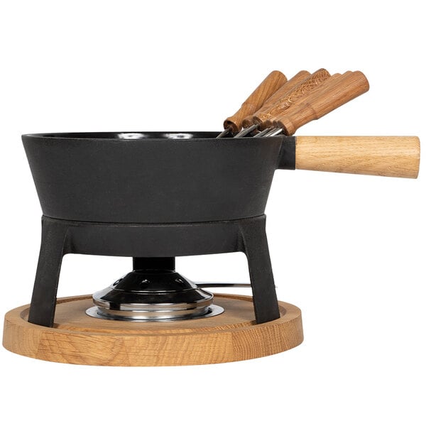 A Boska cast iron fondue set with wooden handles on a wooden stand.