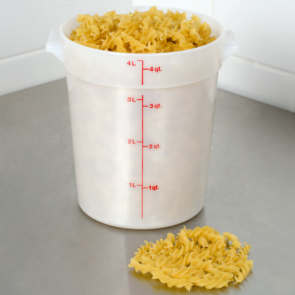 A white Cambro round plastic food storage container with pasta in it and a measuring spoon.