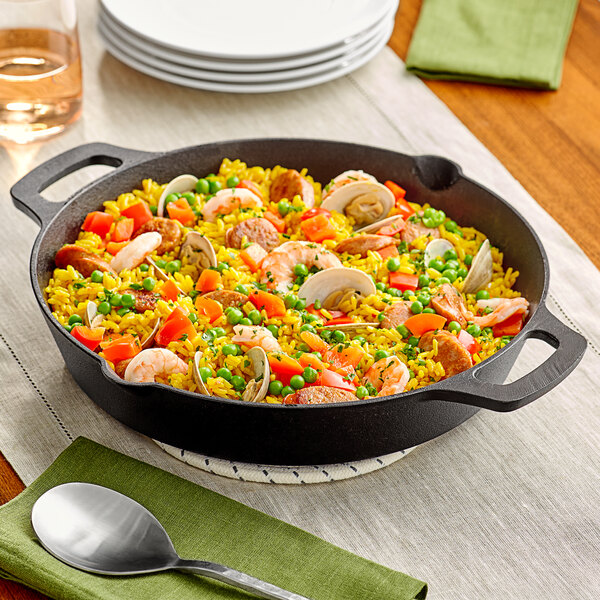 A Valor pre-seasoned cast iron skillet filled with rice, shrimp and vegetables on a table.