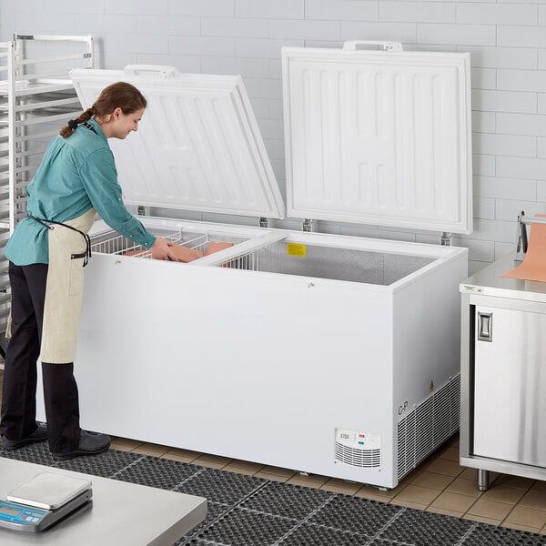 A woman standing in a professional kitchen in front of a Galaxy commercial chest freezer.