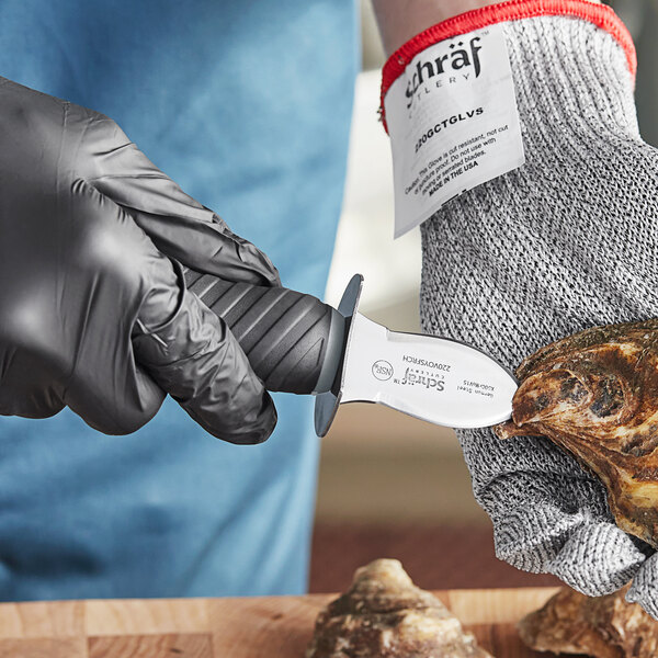 A person in black gloves using a Schraf Frenchman style oyster knife with a TPR grip to cut open an oyster shell.