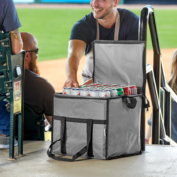 A man standing next to a Choice gray insulated cooler bag full of cans of beer.