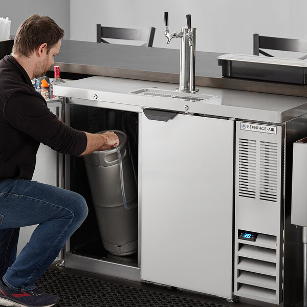 A man putting a keg into a Beverage-Air wine dispenser.