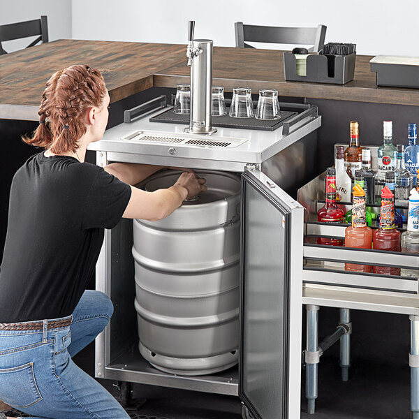 A woman opening a stainless steel Beverage-Air wine kegerator.