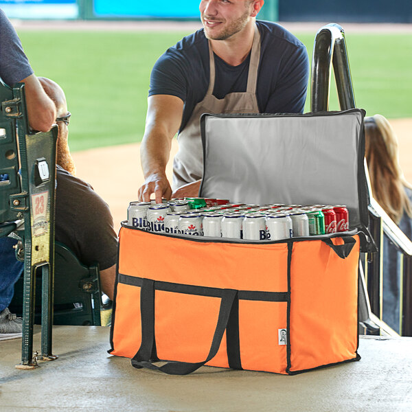 A man in an orange Choice large insulated cooler bag holding cans of soda.