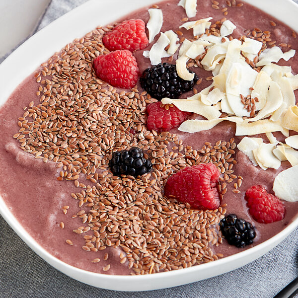A bowl of pink smoothie with berries and Bob's Red Mill gluten-free flax seeds.