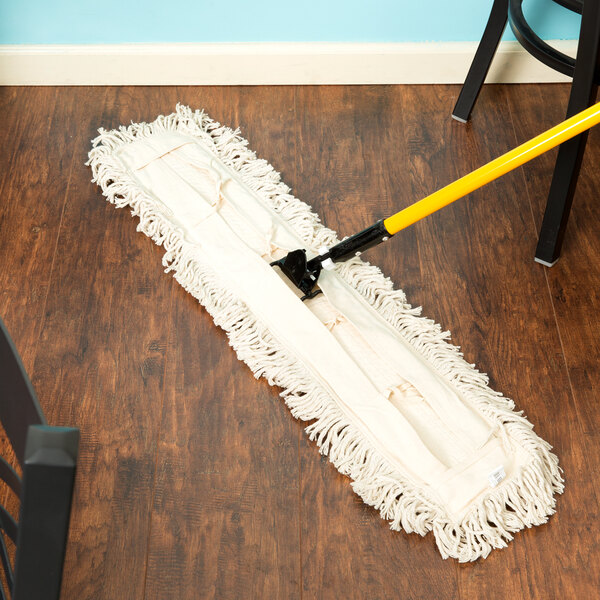 A Carlisle dry dust mop pad on a wood floor.
